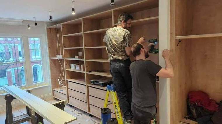 Joiners fitting bespoke shelving and cabinetry